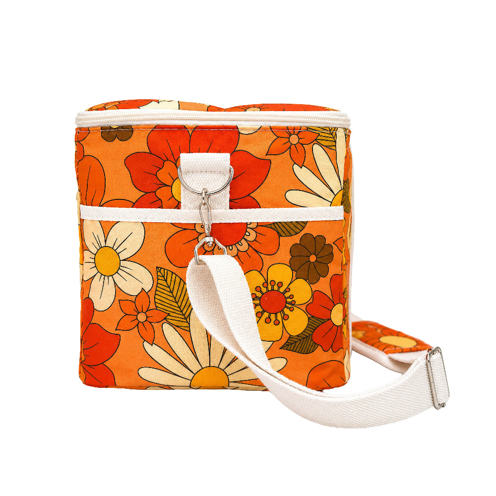 An orange insulated cooler bag with a retro 1970s floral pattern in red, yellow, white, and green, featuring a white shoulder strap and zipper closure.