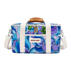 A rectangular duffel bag with a retro 1970s psychedelic floral pattern in blue, purple, and green on a white base. It features white canvas handles and a shoulder strap, a brown leather top handle, and a front label that reads 'SHEDS OF RAIN'.