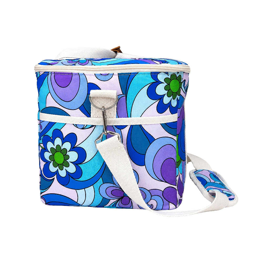 A square soft-sided cooler bag with a retro 1970s floral pattern in blue, purple, and green, featuring a white strap and zipper closure, shown on a plain white background.