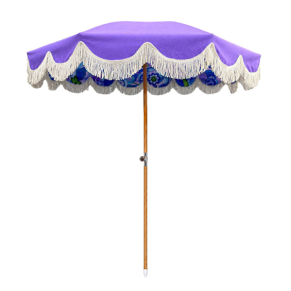 A purple patio umbrella with white fringe trim and a blue floral patterned underside, shown on a plain white background.